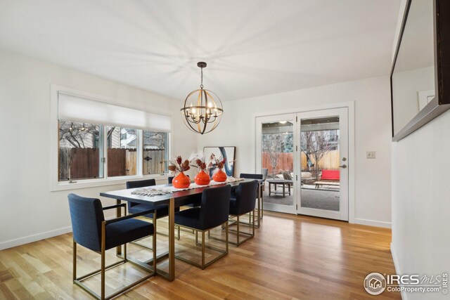 dining space featuring an inviting chandelier, light wood-type flooring, and baseboards