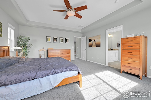 bedroom featuring a ceiling fan, baseboards, ensuite bathroom, and light carpet