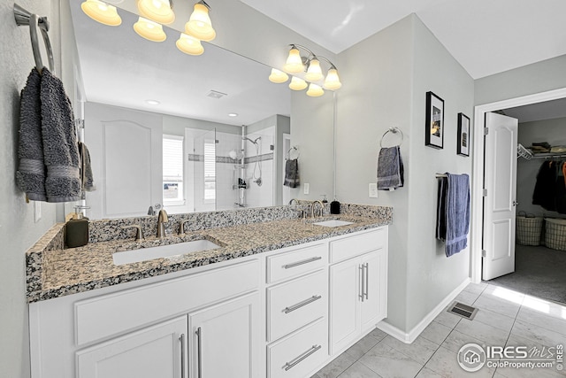 full bathroom with double vanity, visible vents, a stall shower, and a sink