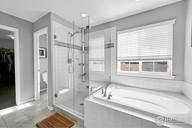 bathroom with a spacious closet, a shower stall, toilet, and a garden tub