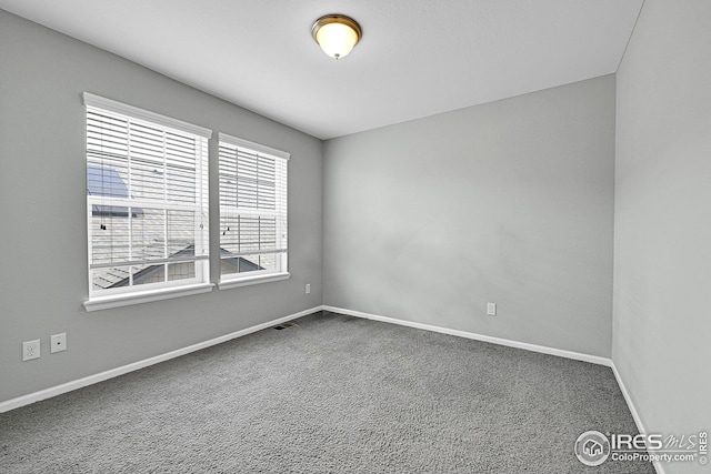 unfurnished room with visible vents, baseboards, and dark carpet