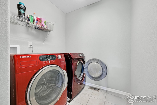 clothes washing area with tile patterned flooring, baseboards, laundry area, and washing machine and clothes dryer