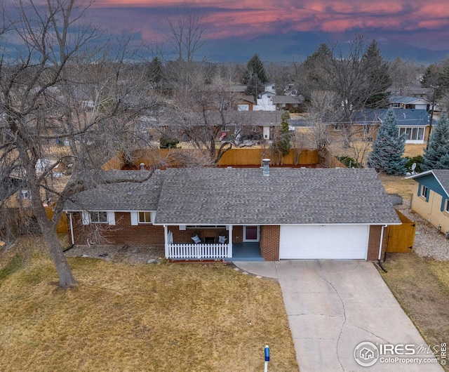 single story home with brick siding, an attached garage, a shingled roof, and a yard