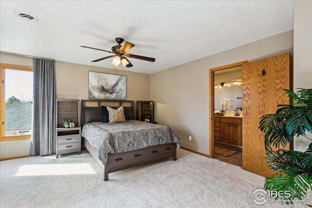 carpeted bedroom with a ceiling fan, baseboards, visible vents, ensuite bath, and a sink