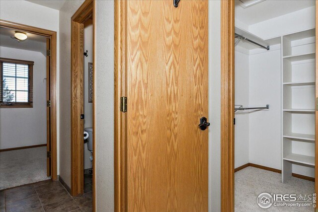 hallway featuring baseboards and carpet floors