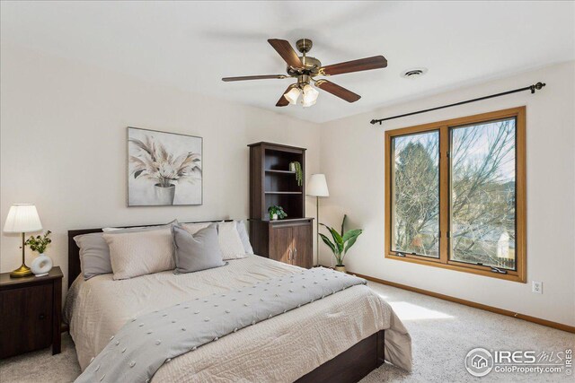 bedroom featuring light carpet, visible vents, a ceiling fan, and baseboards