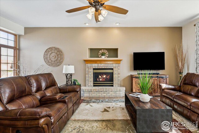 living area featuring a fireplace and ceiling fan