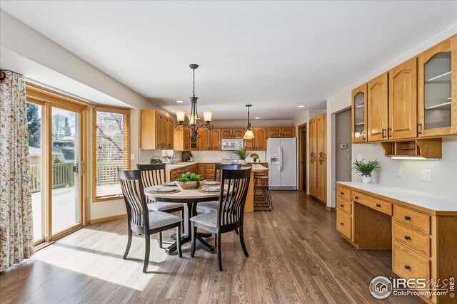 dining room featuring baseboards, built in desk, recessed lighting, an inviting chandelier, and wood finished floors