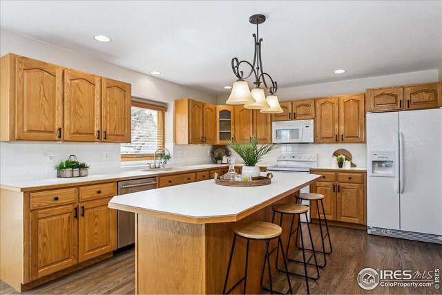 kitchen featuring white appliances, light countertops, dark wood-style flooring, and a center island