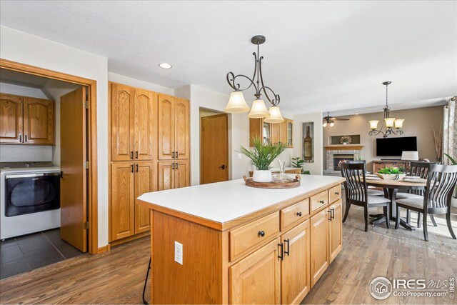 kitchen featuring washer / dryer, a fireplace, a kitchen island, and wood finished floors