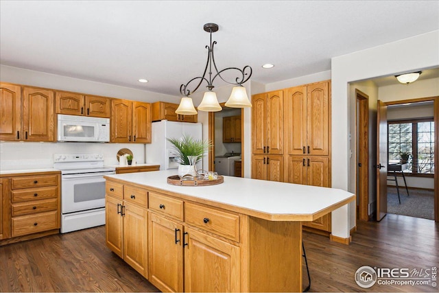 kitchen with white appliances, a kitchen island, dark wood finished floors, light countertops, and decorative light fixtures