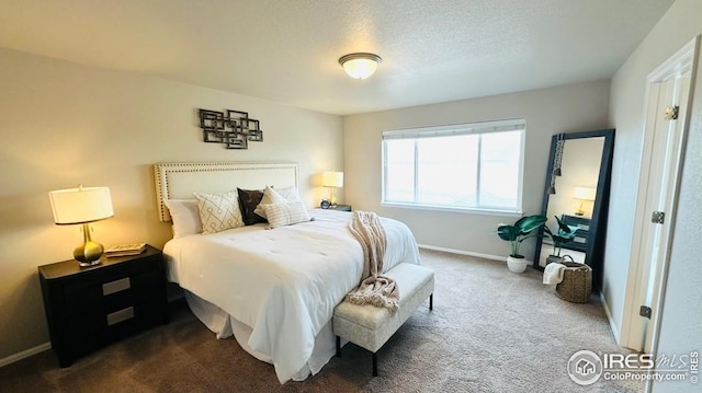 bedroom featuring baseboards, dark colored carpet, and a textured ceiling