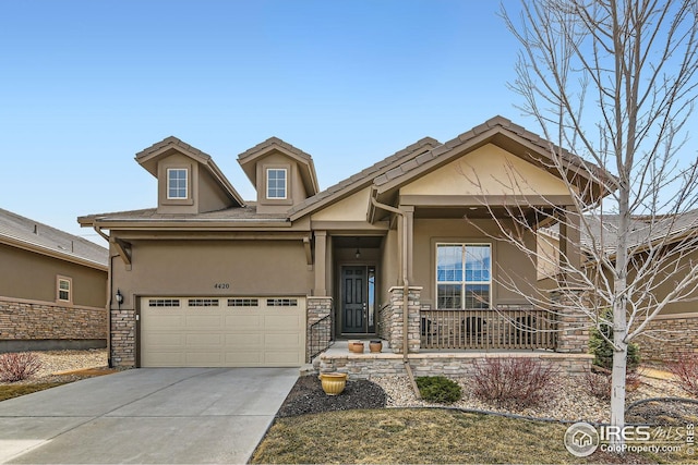 craftsman house featuring driveway, an attached garage, covered porch, stucco siding, and stone siding