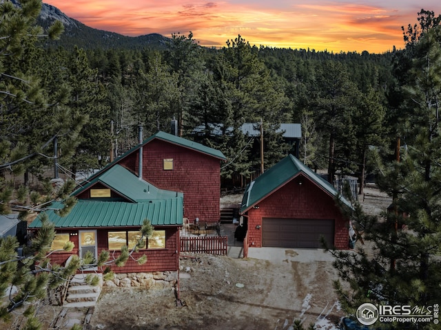 view of front of home with a mountain view, an outbuilding, metal roof, and a wooded view