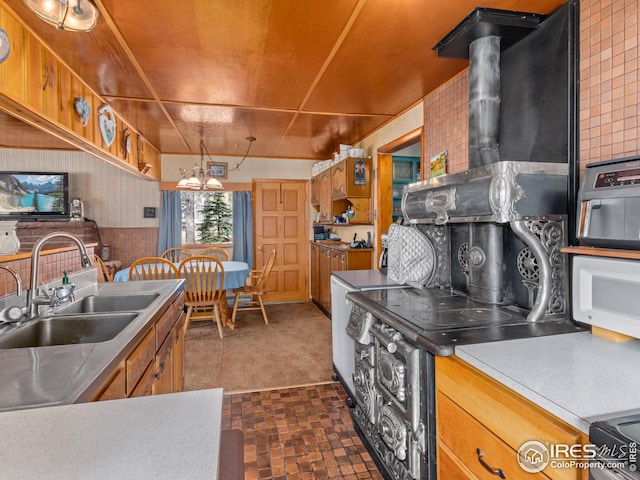 kitchen featuring brown cabinets, stainless steel range with electric cooktop, a wood stove, a notable chandelier, and a sink