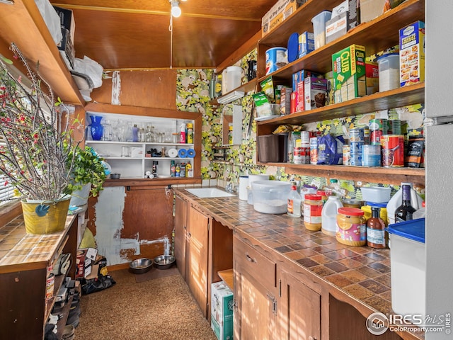 kitchen with open shelves, tile counters, and a sink