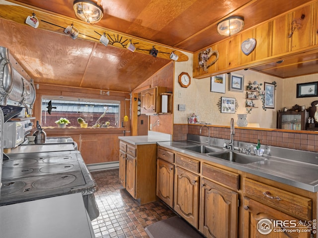 kitchen with brown cabinetry, a peninsula, a sink, stainless steel counters, and a baseboard heating unit