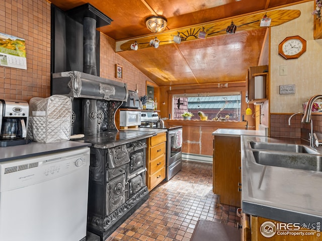 kitchen with a sink, stainless steel countertops, white appliances, decorative backsplash, and lofted ceiling