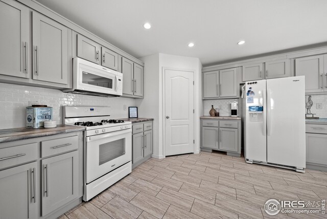 kitchen with decorative backsplash, white appliances, recessed lighting, and gray cabinets