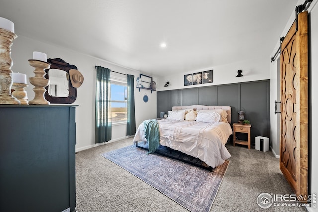 bedroom featuring a barn door, carpet, and baseboards