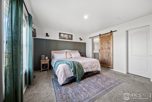 bedroom with a barn door, carpet floors, and ensuite bath