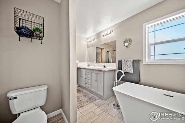 full bathroom featuring a shower with shower door, double vanity, a freestanding tub, a sink, and toilet