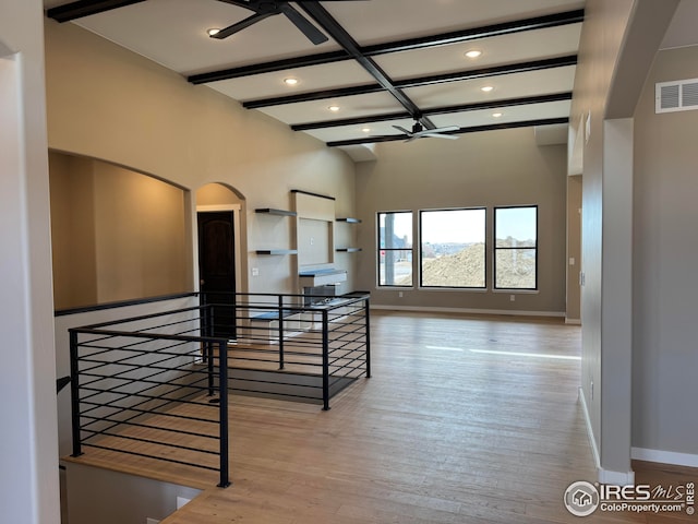 interior space with wood finished floors, visible vents, baseboards, beam ceiling, and an upstairs landing