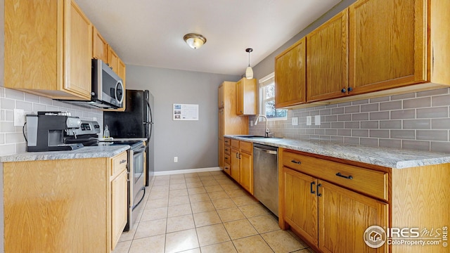 kitchen featuring baseboards, light tile patterned flooring, a sink, stainless steel appliances, and light countertops