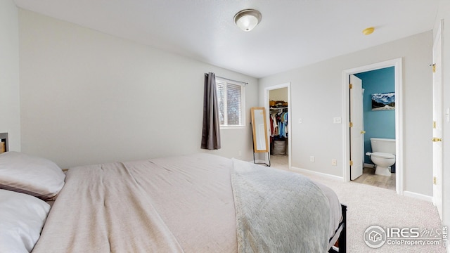 carpeted bedroom with a walk in closet, ensuite bath, baseboards, and a closet