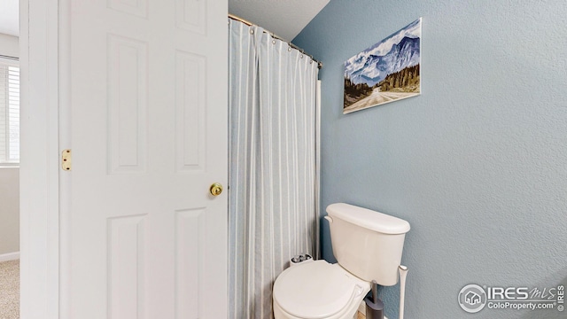 bathroom with toilet and a textured wall