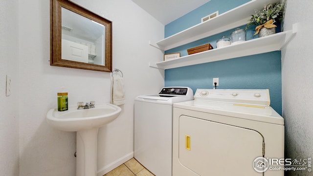 laundry room featuring light tile patterned floors, visible vents, washing machine and clothes dryer, laundry area, and a sink