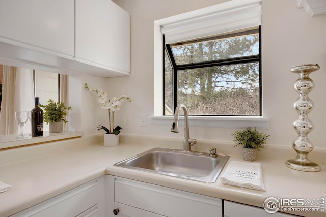 kitchen with white cabinets, light countertops, and a sink