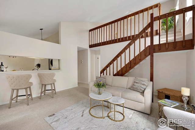 carpeted living room with high vaulted ceiling and stairs