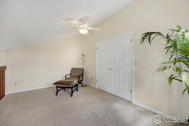 sitting room with vaulted ceiling, baseboards, and a textured ceiling