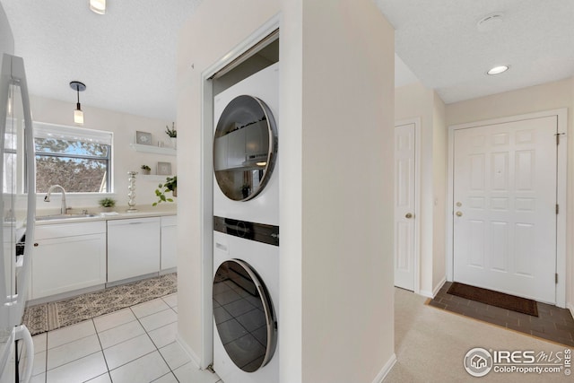 laundry room with stacked washer / dryer, recessed lighting, light tile patterned flooring, a textured ceiling, and a sink