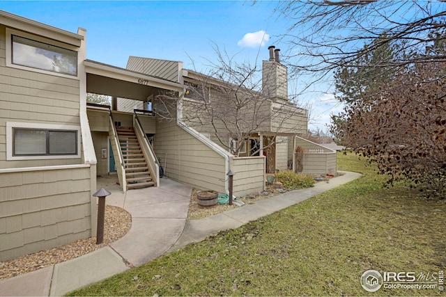 exterior space with a front yard, stairway, and a chimney