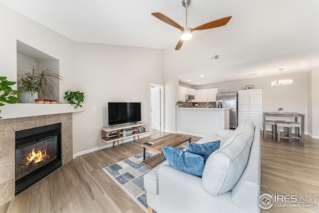 living room with visible vents, a fireplace, light wood-type flooring, and baseboards