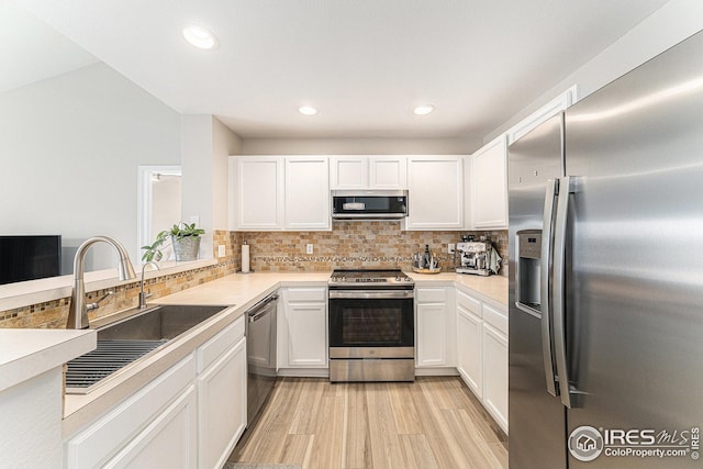 kitchen with tasteful backsplash, white cabinets, stainless steel appliances, and a sink