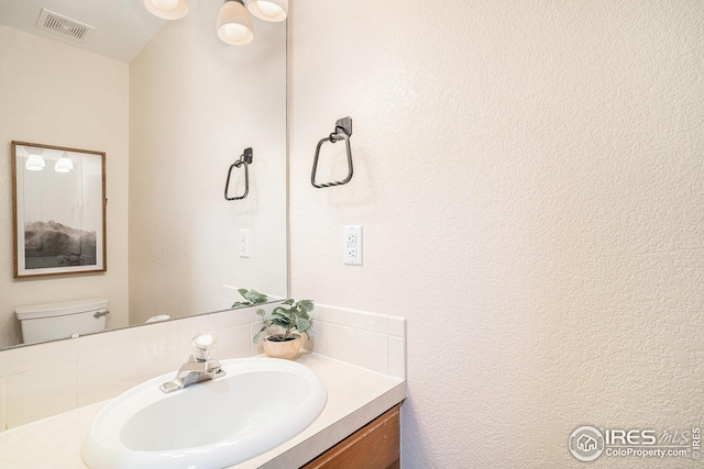 half bath with visible vents, toilet, and vanity