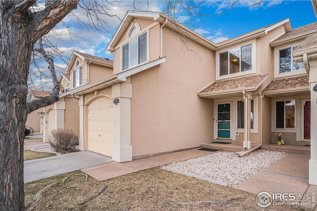 view of front of property featuring roof with shingles, an attached garage, driveway, and stucco siding