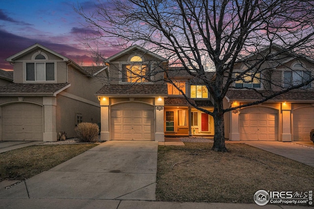 traditional home with stucco siding, driveway, and a garage