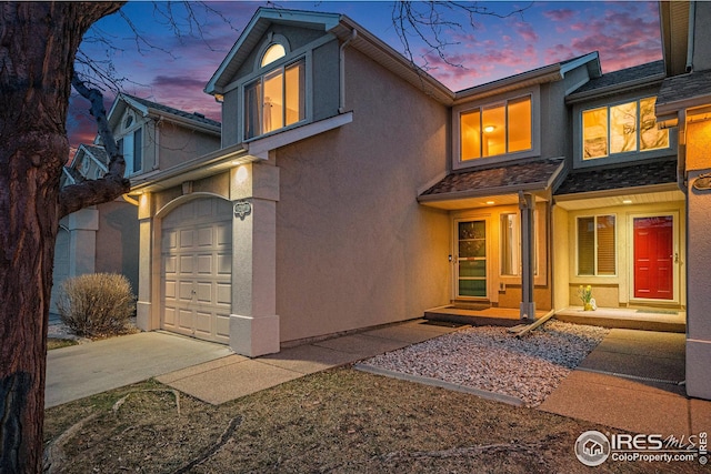 exterior space featuring a garage, driveway, and stucco siding