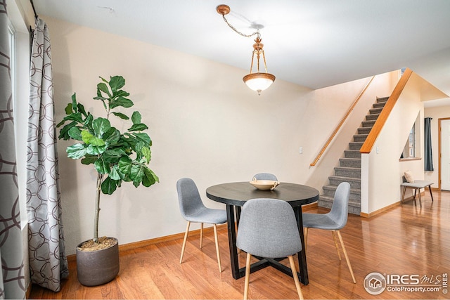 dining room with stairs, baseboards, and wood finished floors