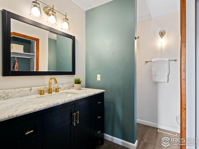 bathroom featuring visible vents, vanity, baseboards, and wood finished floors