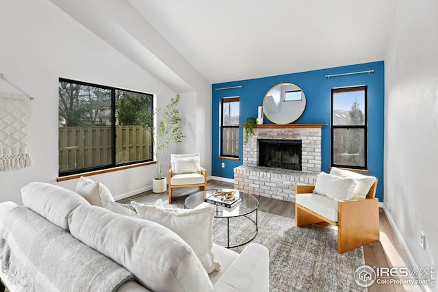 living room featuring a fireplace, vaulted ceiling, wood finished floors, and baseboards