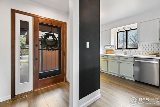 kitchen featuring wood finished floors, visible vents, a sink, stainless steel dishwasher, and tasteful backsplash