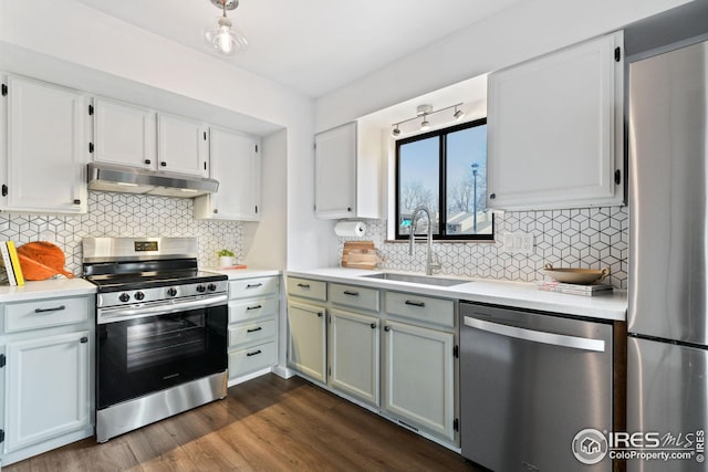 kitchen featuring dark wood-style floors, a sink, stainless steel appliances, light countertops, and under cabinet range hood