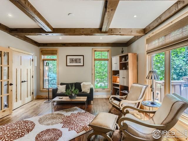 living area featuring a wealth of natural light, baseboards, beam ceiling, and wood finished floors