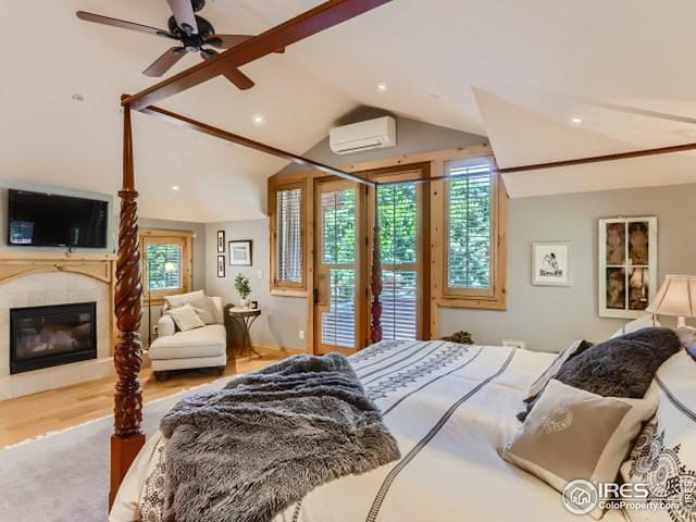 bedroom featuring a tiled fireplace, a wall mounted air conditioner, vaulted ceiling, wood finished floors, and access to outside
