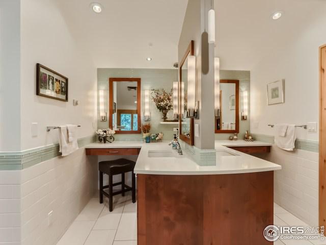 bathroom featuring a wainscoted wall, recessed lighting, tile walls, tile patterned flooring, and vanity